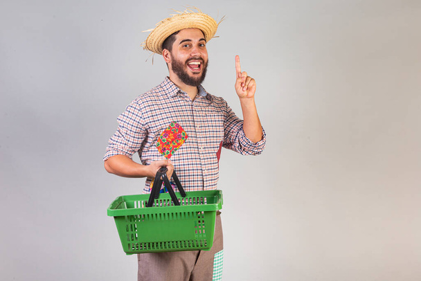 Brazilian man wearing festa junina clothes. Arraial, Feast of Saint John. with supermarket basket. - Foto, imagen