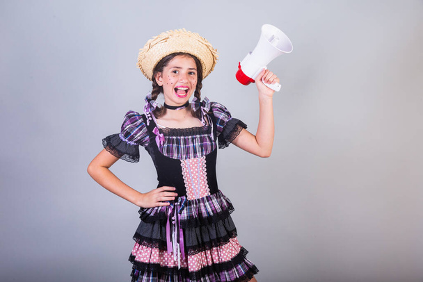 Girl, Brazilian, with clothes from Festa Junina, Arraial, Festa de So Joo. Horizontal portrait. With megaphone, advertising promotion.  - Fotoğraf, Görsel