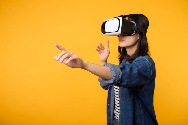 Asian young woman get experienced wearing virtual reality headset game entertainment isolated on yellow background. Winner of cyber future video game concept. - Photo, Image