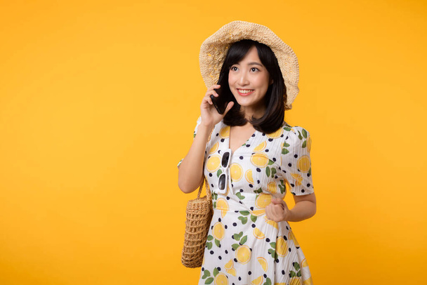 Sarı arka planda izole edilmiş mobil reklam uygulaması kullanan, bahar dönemi elbise modasına sahip mutlu Asyalı genç bir kadın portresi. Akıllı telefon uygulama teknolojisi kavramı. - Fotoğraf, Görsel