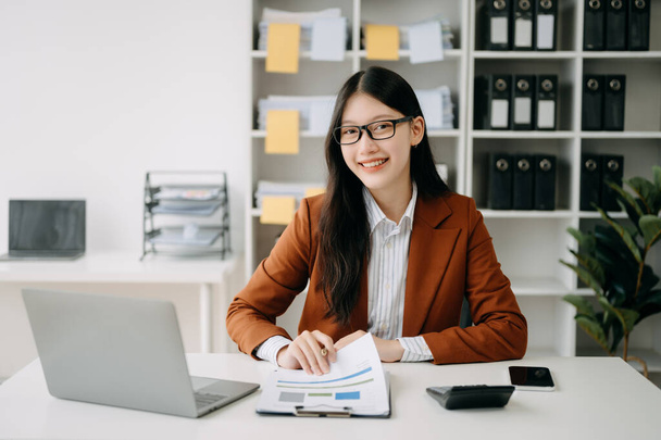 Confident beautiful Asian businesswoman with laptop  and phone at modern office - Foto, immagini