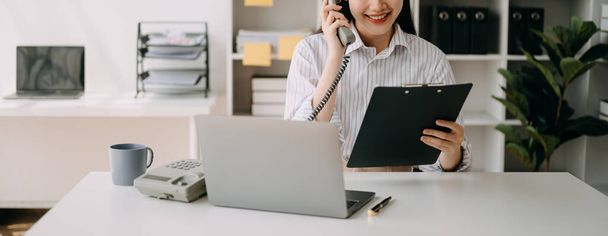 Mujer de negocios utilizando el teléfono y el ordenador portátil en el escritorio como concepto en la luz de la mañana - Foto, Imagen