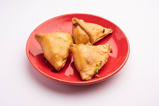 Indian sweet samosa is a Fried pastry soaked in sugar syrup filled with coconut, nuts and fruits - Photo, Image
