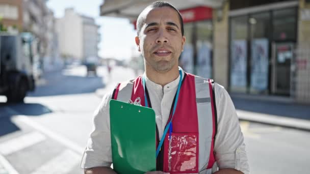 Jonge Spaanse man vrijwilliger die klembord vasthoudt en op straat spreekt - Video