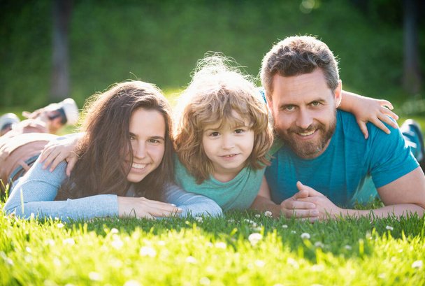 Πορτρέτο μιας χαρούμενης οικογένειας που αγκαλιάζεται στο πάρκο. Οικογένεια και παιδί σε εξωτερικούς χώρους το καλοκαίρι φύση - Φωτογραφία, εικόνα