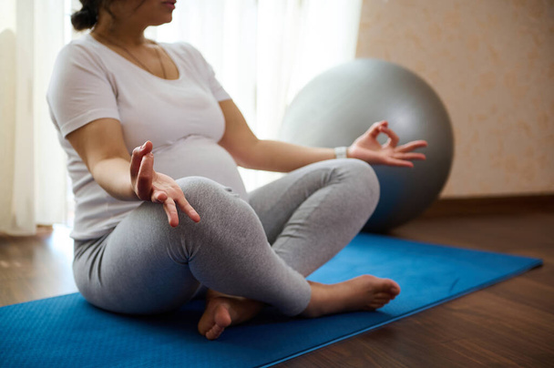 Зблизька вагітна жінка йогі тримає пальці в жесті мудри, медитуючи, досягаючи дзен, рівноваги і гармонії, відчуваючи спокій, позитивне і розслаблене. Тренування йоги. Медитація на здорову вагітність - Фото, зображення