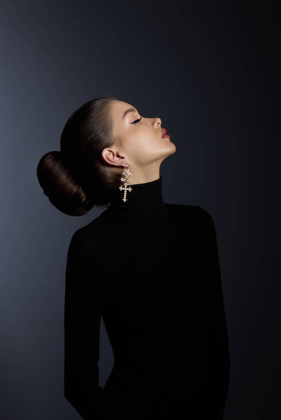 Perfect art woman in black turtleneck on a dark background. Brunette long hair is pulled into a bun. Evening makeup - Photo, Image