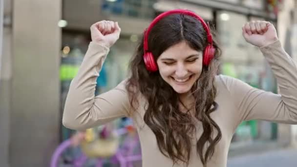 Nuori kaunis latino nainen hymyilee luottavainen kuunnella musiikkia tanssia kadulla - Materiaali, video