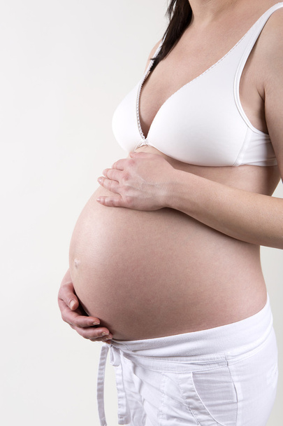 Donna incinta davanti a uno sfondo bianco
 - Foto, immagini