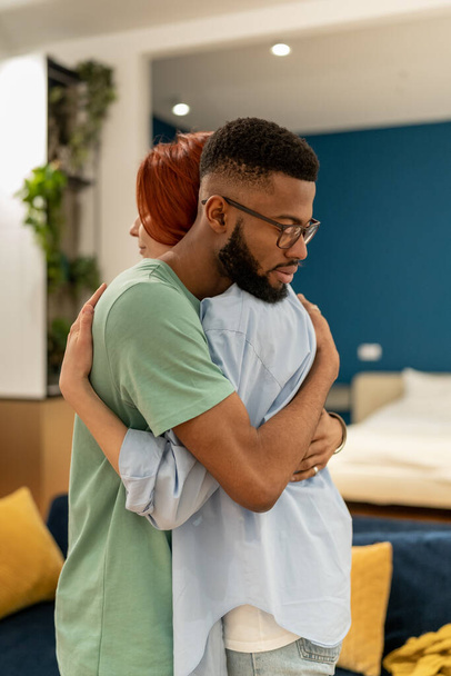 Young multiracial couple man and woman hugging while making up at home, loving supportive husband embracing wife gently, showing love and support. Understanding in relationships,  - Fotó, kép