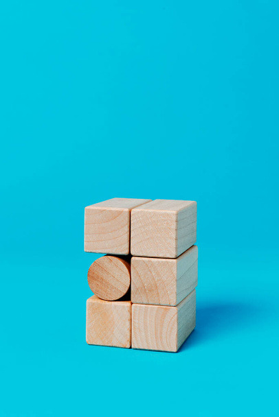 циліндричний іграшковий блок у стосі з прямокутних іграшкових блоків, на синьому фоні з порожнім простором зверху
 - Фото, зображення