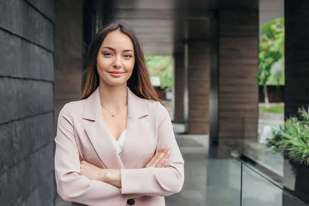 Portret van een succesvolle zakenvrouw met gevouwen handen op de achtergrond van een kantoorgebouw. Vrouwelijke bedrijfsadviseur analist. kopieerruimte - Foto, afbeelding