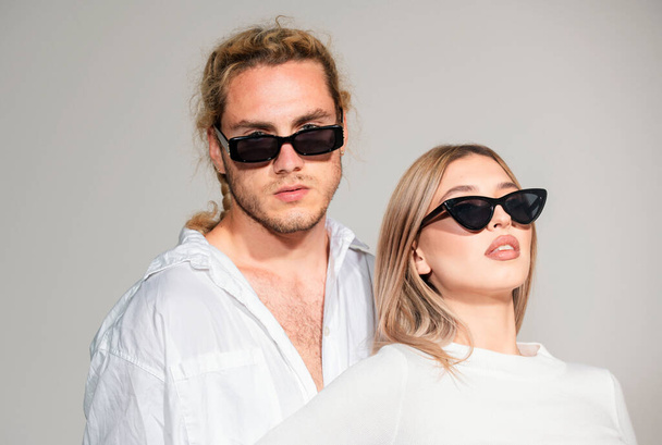 Couple in fashion black sunglasses. Young couple posing with sunglasses. Vogue Style. High fashion look in vogue style. Couple in love on date in formal fashion look. Trendy look - Foto, imagen