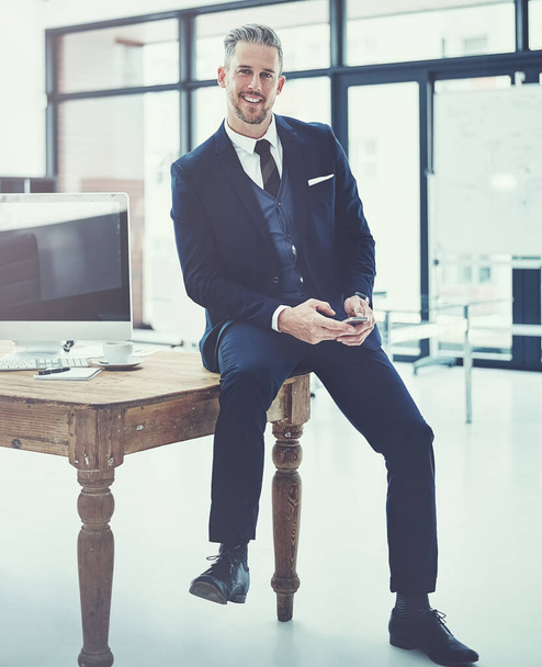 Бизнес это бриз с умными технологиями. зрелый бизнесмен, использующий мобильный телефон за своим столом в современном офисе - Фото, изображение