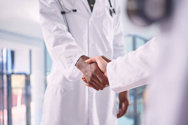 Великий доктор полезен для любой больницы. Два неузнаваемых врача пожимают руки, стоя в больнице - Фото, изображение