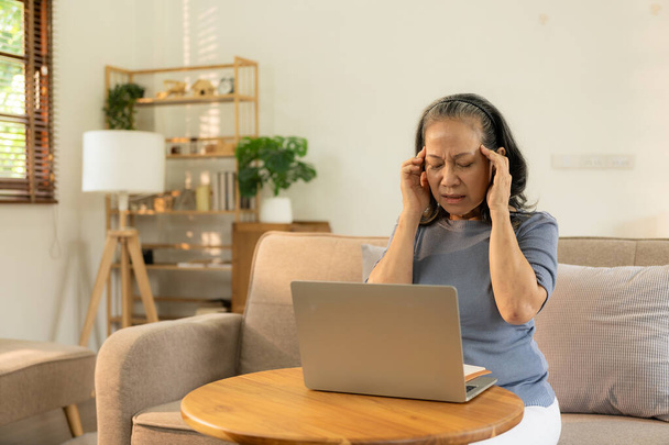 Mulher idosa, problemas de saúde, visão e pessoas. Close up de asiática velha mulher sentada no sofá e tendo dor de cabeça em casa de trabalhar na frente do laptop. - Foto, Imagem