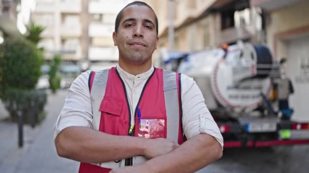 Giovane uomo ispanico volontario sorridente indossa giubbotto antiproiettile in strada - Filmati, video