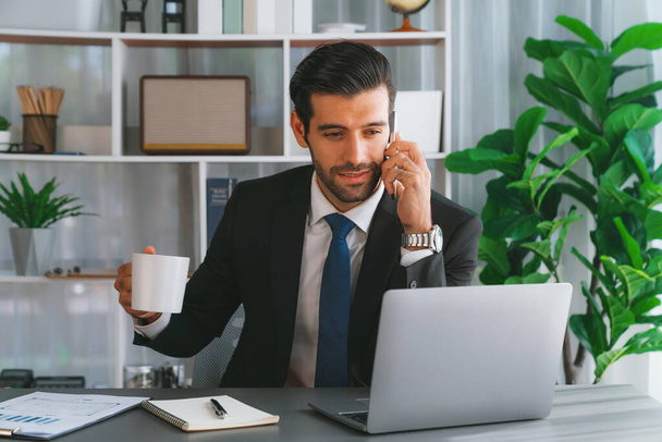 Ahkera liikemies kiireinen puhua puhelun asiakkaiden kanssa työskennellessään kannettavan tietokoneen toimistossaan käsitteenä modernin ahkera toimistotyöntekijä elämäntapa matkapuhelimella. Kiihkeä - Valokuva, kuva
