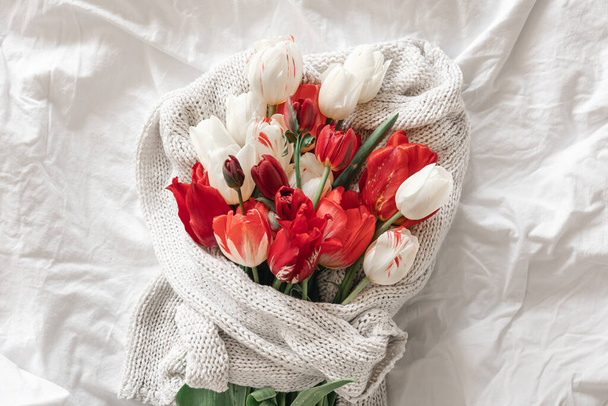 Spring background with a bouquet of red tulips in a white bed, top view. - Zdjęcie, obraz