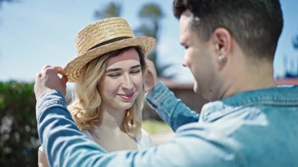 Hombre y mujer pareja sonriendo confiado usando sombrero de verano en la calle - Imágenes, Vídeo