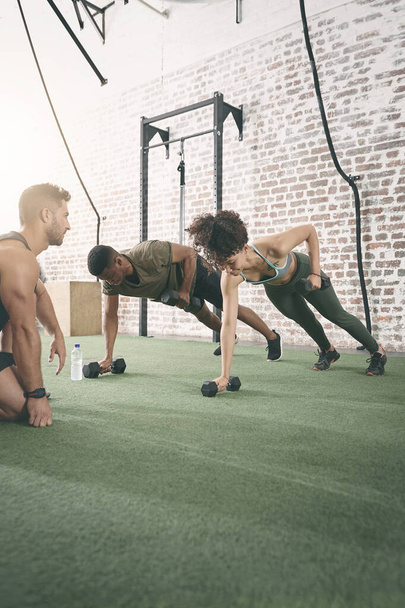 Trabajando los brazos, hombros, espalda y pecho. dos personas haciendo ejercicio con un instructor de fitness en el gimnasio - Foto, Imagen