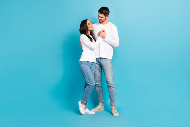 Full body photo of two idyllic positive people cuddle look each other hold hands isolated on blue color background. - Foto, immagini