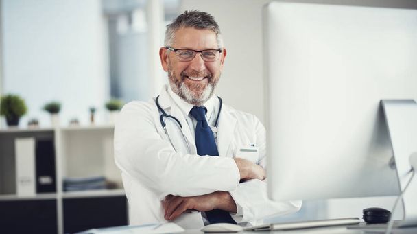 Nel mio ufficio, la tua salute viene prima di tutto. Ritratto di un medico maturo che usa un computer su una scrivania nel suo ufficio - Foto, immagini