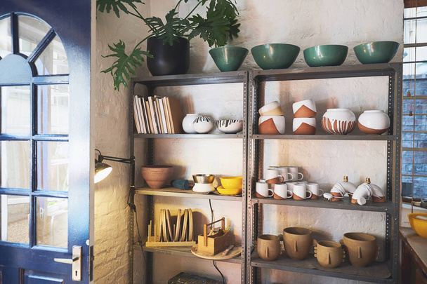 How far a ball of clay has come. various vases and pots on a shelf in a pottery studio - Fotoğraf, Görsel