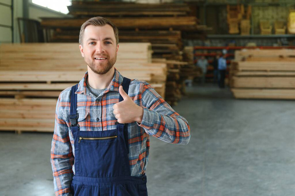 Young man carpenter at the wooden warehouse. Copy space for text, - 写真・画像