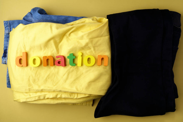 Džíny s nápisem darování, koncept pomoci lidem v nouzi. Dát charitě, žluté pozadí - Fotografie, Obrázek