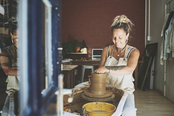 ものづくりは自己発見の一形態です。陶芸の工房で粘土を扱う若い女性が - 写真・画像