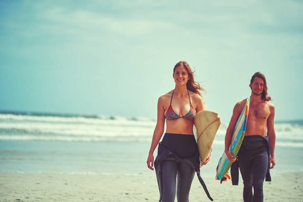 Podemos soportar aguas tormentosas. una joven pareja caminando por la playa con sus tablas de surf - Foto, Imagen