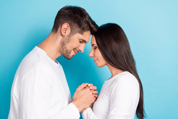 Photo of two pleasant adorable optimistic couple people wear white shirts holding hands together isolated on blue color background. - Foto, Bild