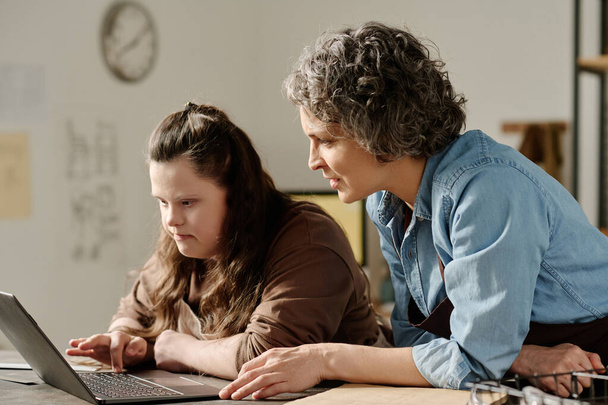 Столяр обсуждает онлайн-проект на ноутбуке с девушкой с синдромом пуха во время работы в мастерской - Фото, изображение