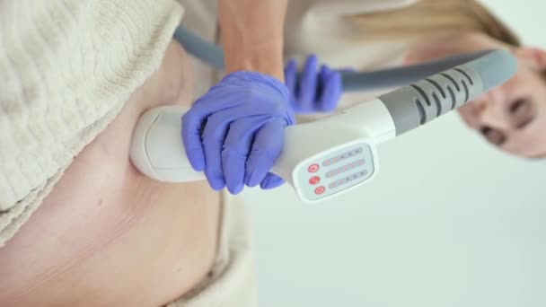 Professzionális kozmetikus kesztyű segítségével zsír eltávolító gép hasán ügyfél kozmetikai klinika - Felvétel, videó