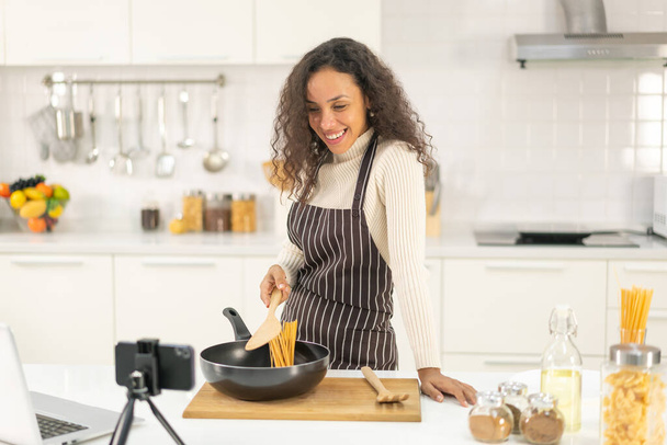 Latin kadın blogda paylaşmak için mutfakta video ve yemek çekiyor. - Fotoğraf, Görsel