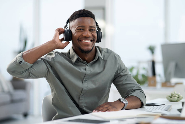 Hombre negro, auriculares y escuchar música en la oficina con sonrisa para la banda sonora o podcast. Hombre africano feliz o diseñador profesional sonriendo con auriculares disfrutando de audio en el lugar de trabajo. - Foto, imagen