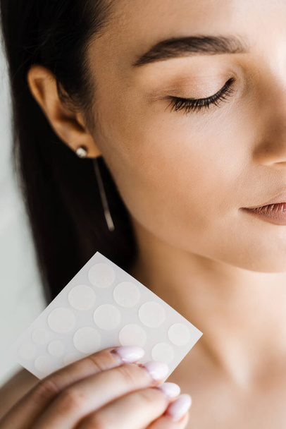 Girl with acne stick round acne patch in hands. Using acne patches for treatment of pimple and rosacea close-up. Facial rejuvenation cleansing cosmetology - Valokuva, kuva