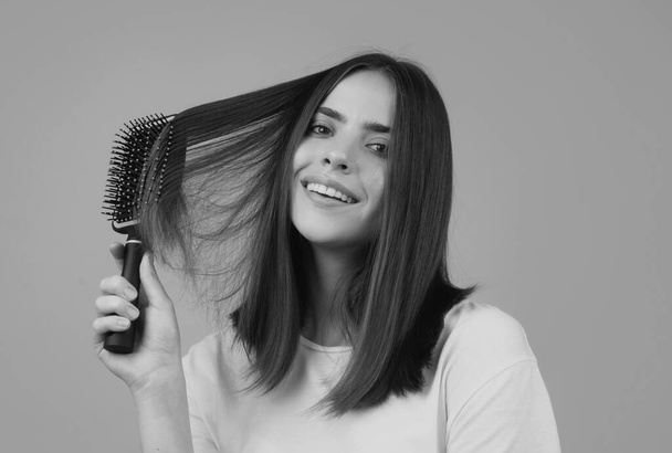 Mulher jovem penteando cabelo brilhante saudável e natural, isolado no estúdio. Cabelo de beleza cuidado - Foto, Imagem