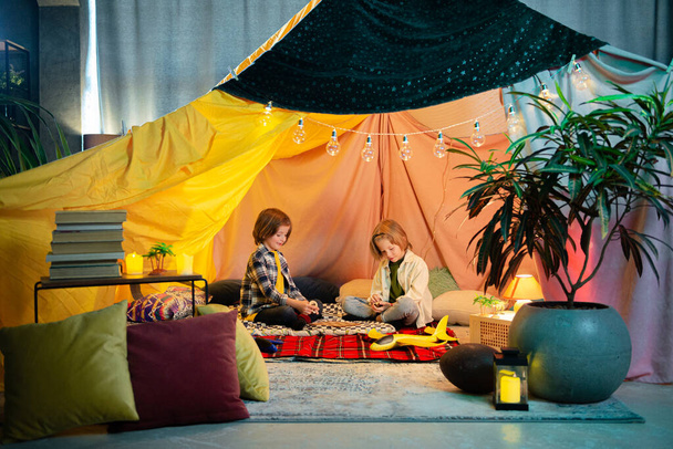 Two boys are laughing and playing together inside a big comfy tent, they re having a lot of fun. - Foto, immagini