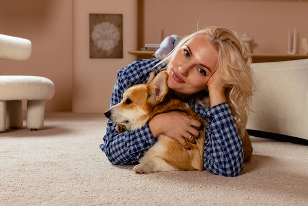 Attractive blonde hair girl and a Welsh corgi Pembroke dog cuddling together. - Photo, Image