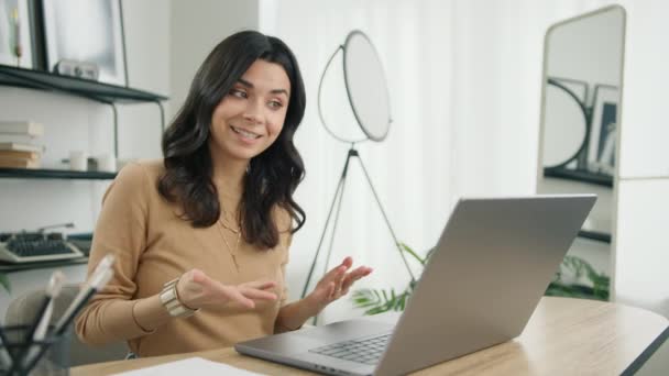 Посміхаючись своїй латиноамериканській студентській електронній освіті з онлайн-репетитором, розмовляючи за допомогою конференц-дзвінка з вчителем. Дівчина на відео чаті вивчає мову, сидить на домашньому офісному столі, виглядає ноутбук комп'ютер повільний рух
 - Кадри, відео