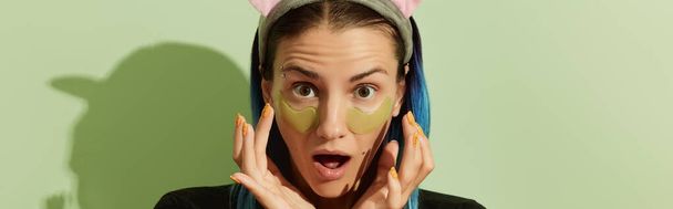 Mujer en pijama con parches en los ojos sobre fondo verde pastel. Concepto de tratamiento de belleza de autocuidado. - Foto, imagen