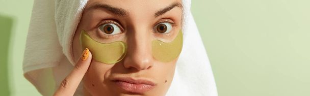 Woman in sunlight with eye patches on pastel green background. Morning skincare routine. Self care beauty treatment concept. - Photo, Image
