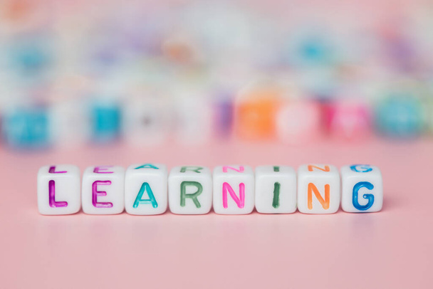 The word LEARNING from letter beads on pink background for education and studying concept, selective focus image - Photo, Image