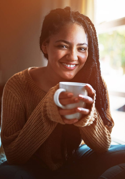 Nothing on my to do list but to relax. Portrait of a happy young woman relaxing with a warm beverage at home - Fotó, kép