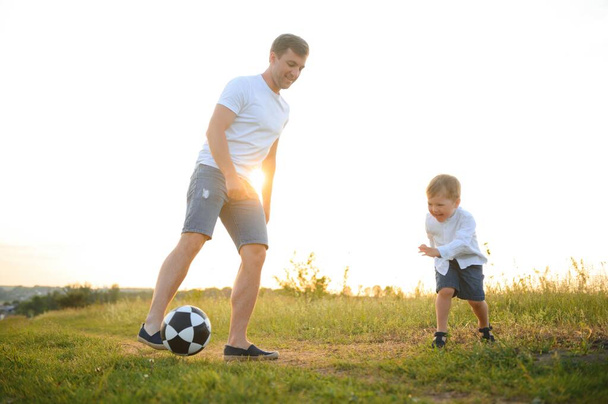 Young father with his little son playing football, father's day - Фото, изображение