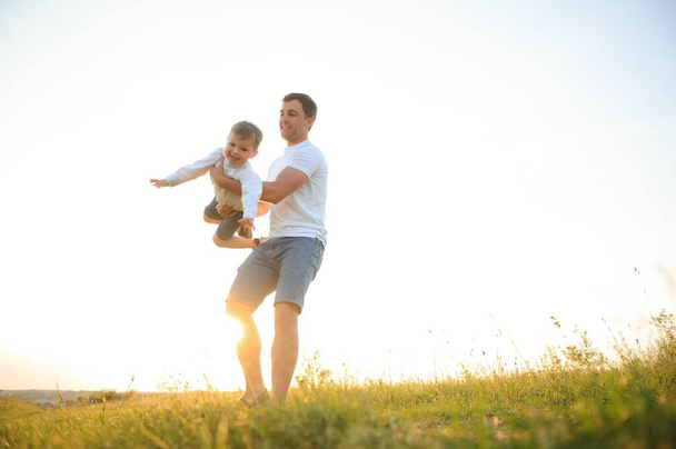 Father's day. Happy family father and toddler son playing and laughing on nature at sunset. - Fotoğraf, Görsel