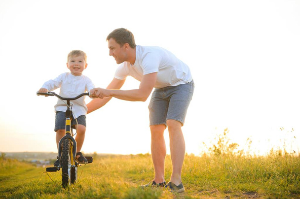 father's day. Dad and son playing together outdoors on a summer. Happy family, father, son at sunset - Foto, Bild