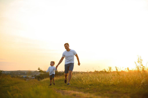 Father's day. Happy family father and toddler son playing and laughing on nature at sunset. - Foto, imagen